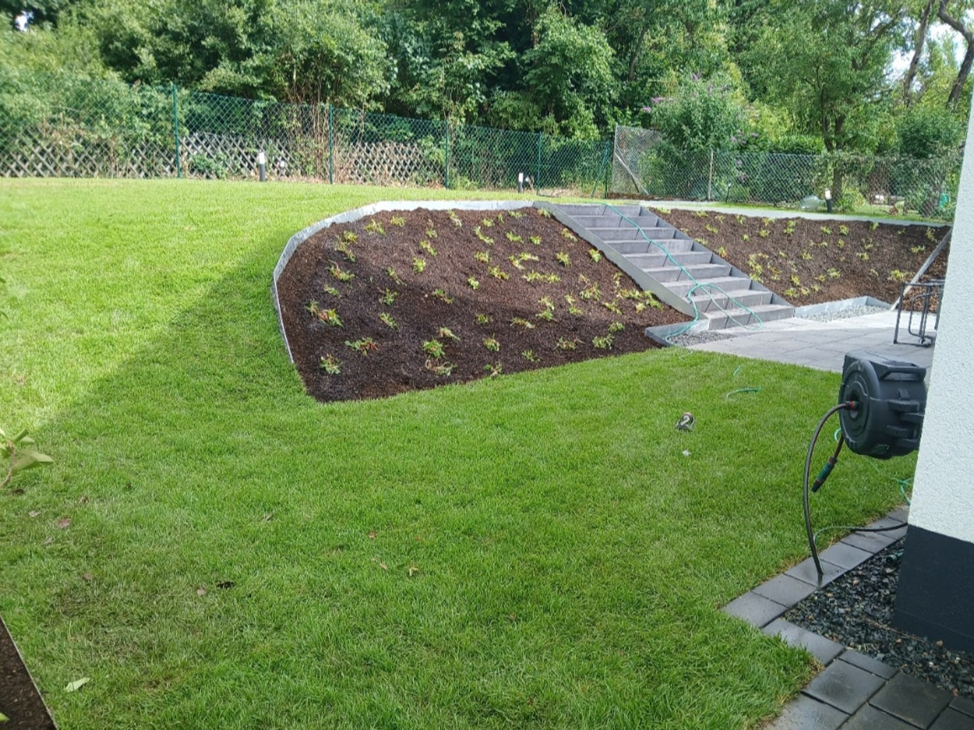 Nachher: modellierter Hang mit Blockstufentreppe, Staudenbeet und Rasen