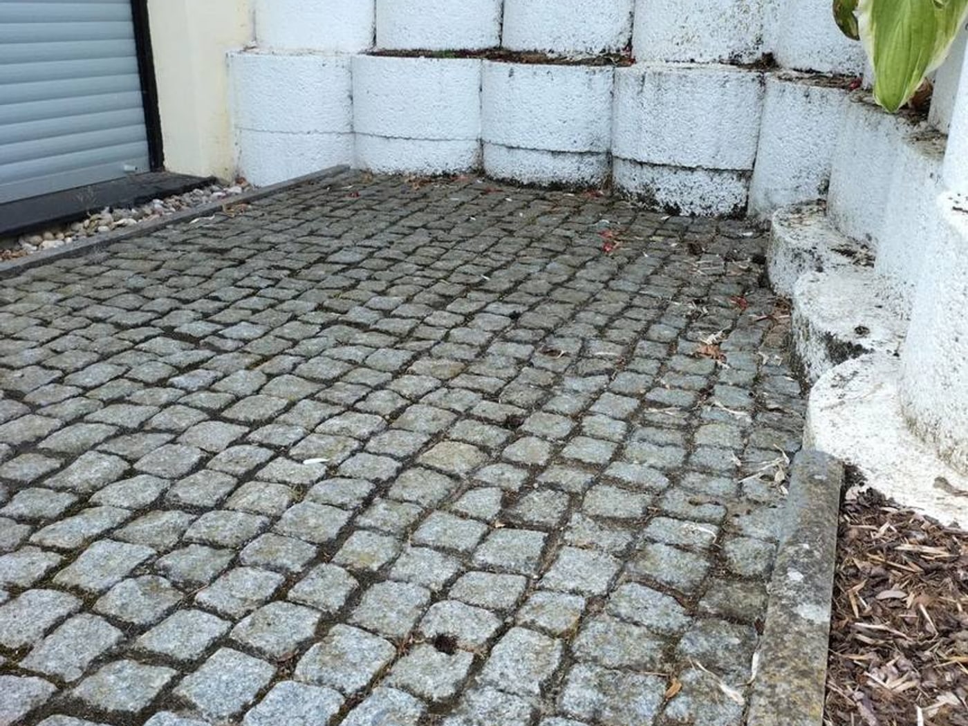 Vorher: weiße Betonstein-Hangmauer über altem Granit-Kleinpflaster