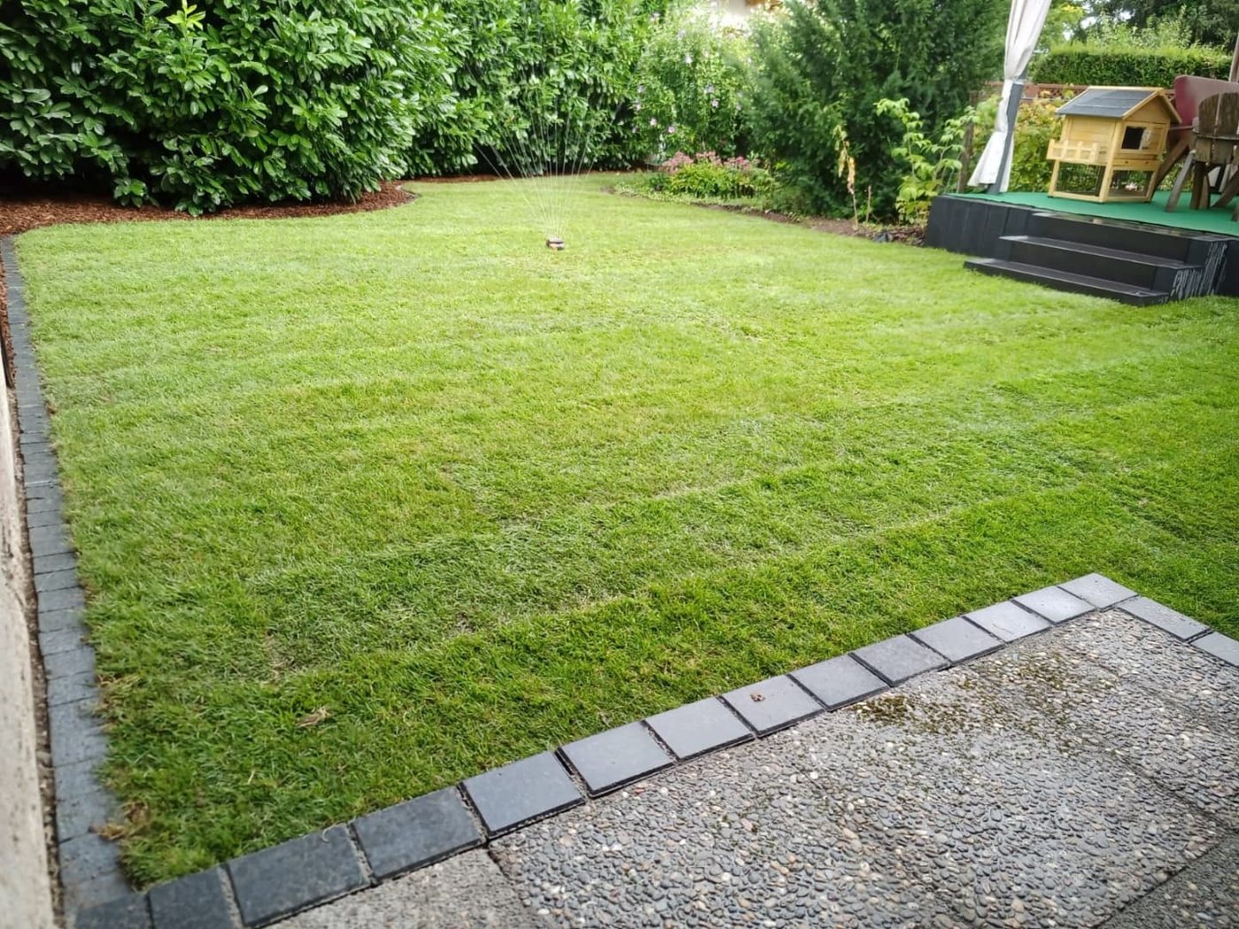 Garten nachher: geschlossene Rasenfläche mit Pflaster-Einfassung