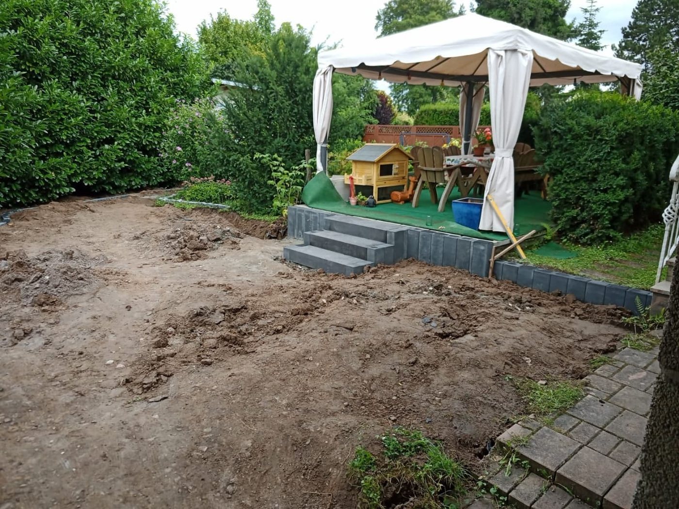 Garten vorher: planierte Erdfläche vor Podest und Hecke